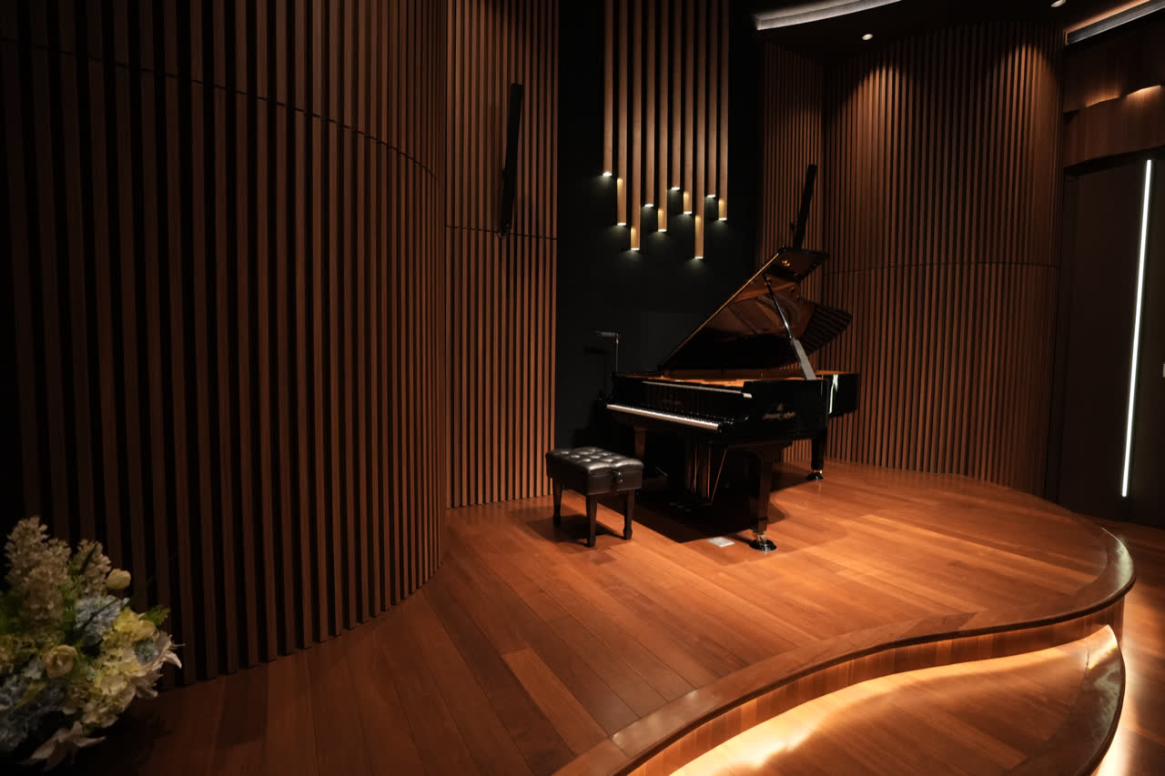 The Shigeru Kawai concert grand, lid open, on the curved timber stage of the hall.